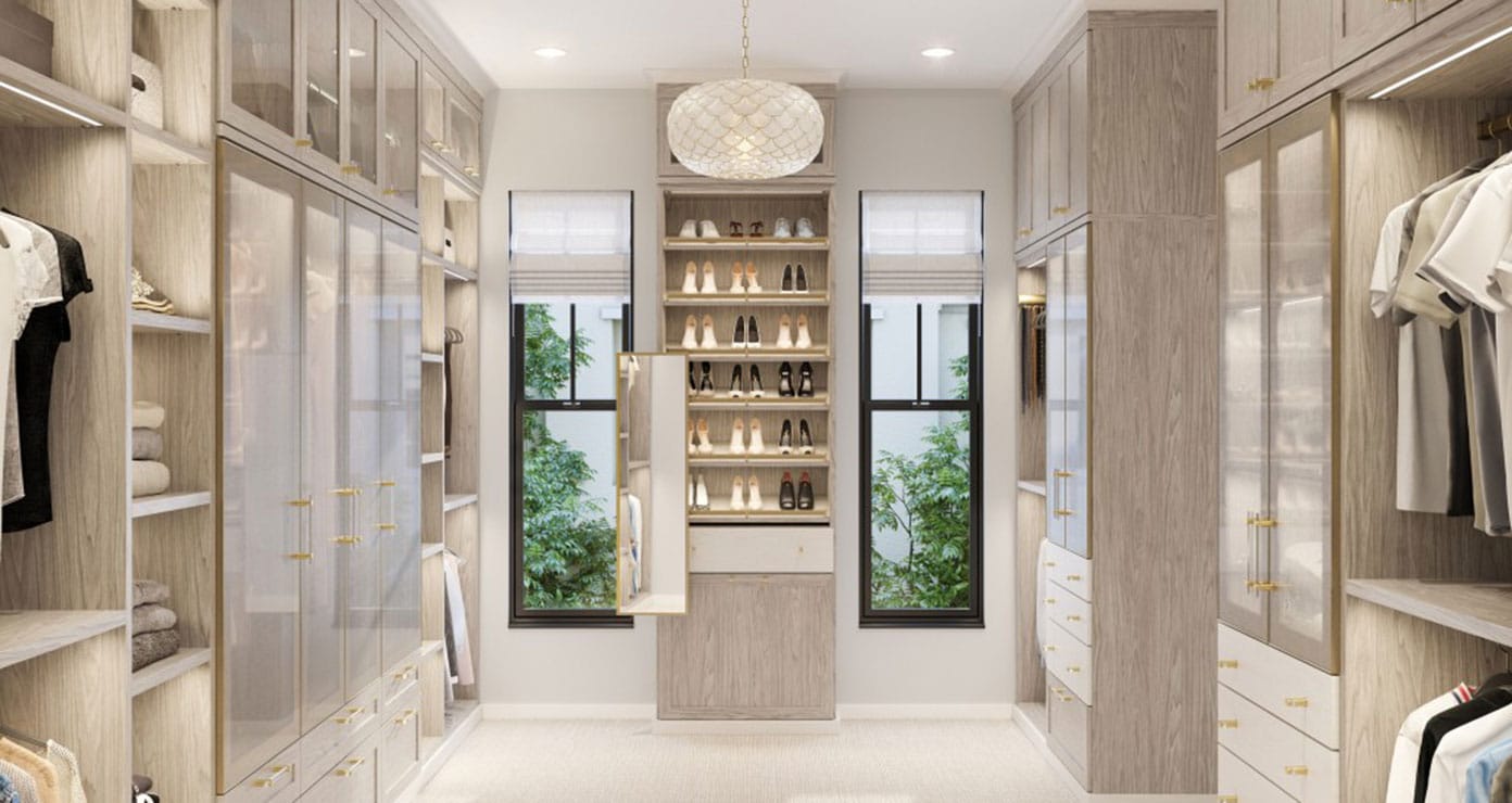 Light finish woman's wardrobe walk in closet designed with glass door cabinets and shoe storage by California Closets