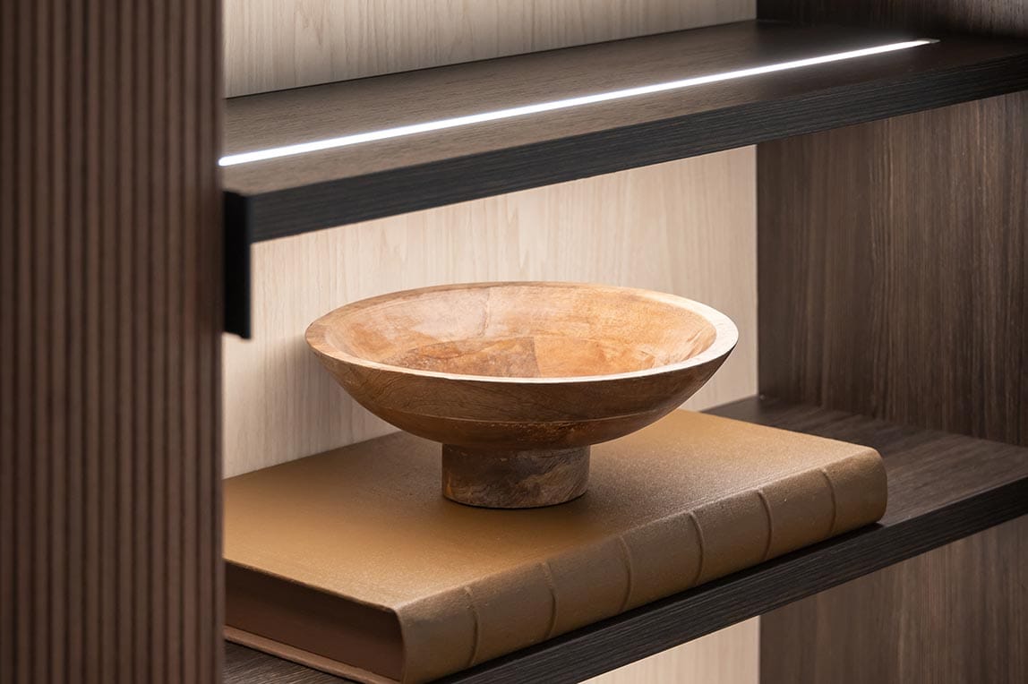 Kitchen pantry shelves with custom lighting in a soft glow by California Closets