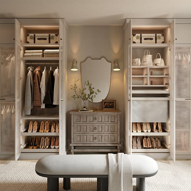 A luxurious walk-in closet featuring shelves neatly arranged with shoes, handbags, and clothing. A central wooden dresser with a decorative mirror and wall sconces is complemented by a cushioned bench in front.