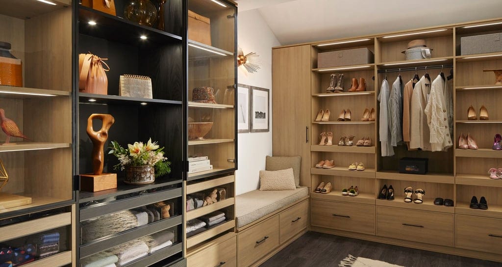 Custom LED lighting in a walk in closet in natural wood grain finish by California Closets