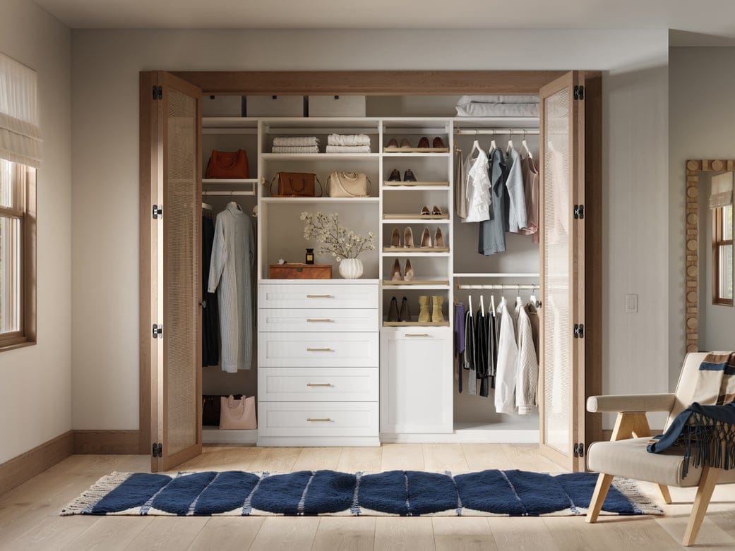 Closet designed with to ceiling storage and dresser drawers in light finish by California Closets